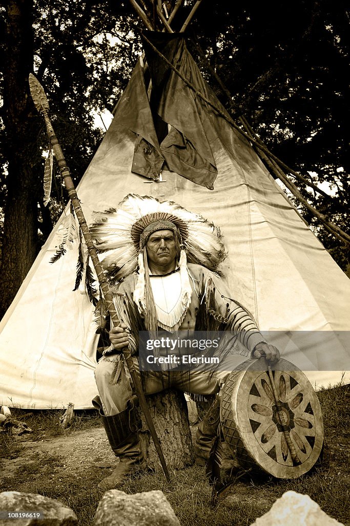 Indianer in traditioneller Kleidung sitzen außerhalb Indianerzelt