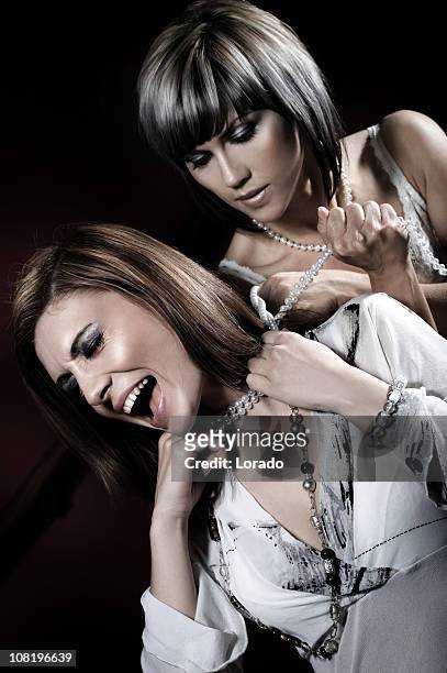 woman choking female with necklace - stabbed in the back stock pictures, royalty-free photos & images