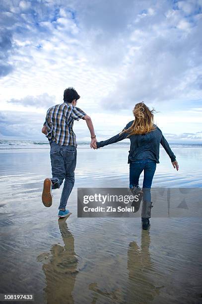 teen couple running on the beach - girls holding hands stock pictures, royalty-free photos & images