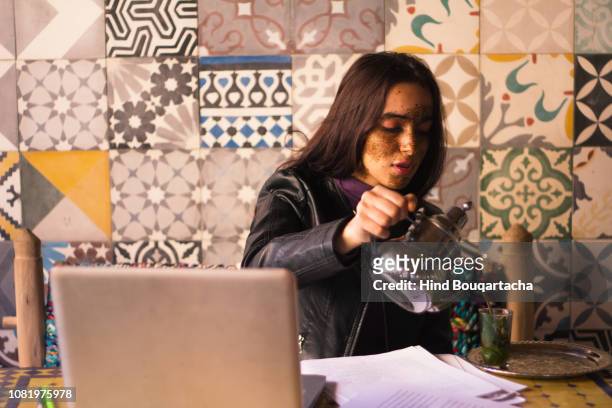 young women pouring tea front of her computer