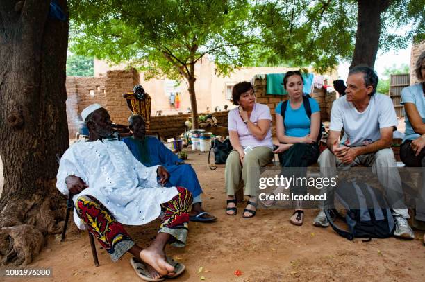 white caucasian people and black african people enjoy life in a rural village. - town meeting stock pictures, royalty-free photos & images