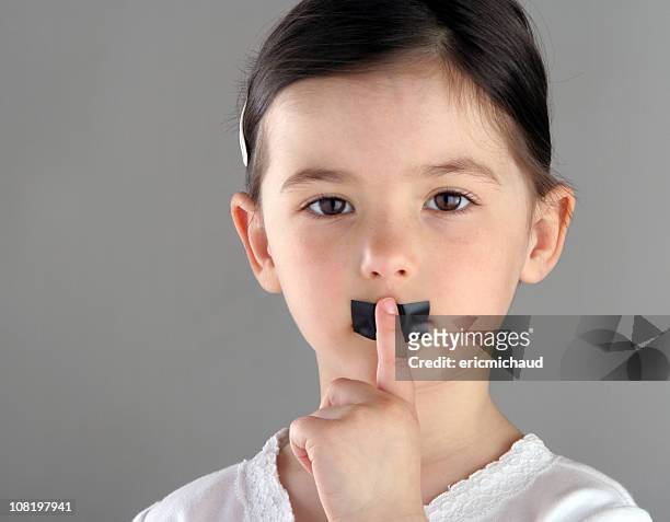 little girl with tape over mouth holding finger to lips - kidnapping stock pictures, royalty-free photos & images