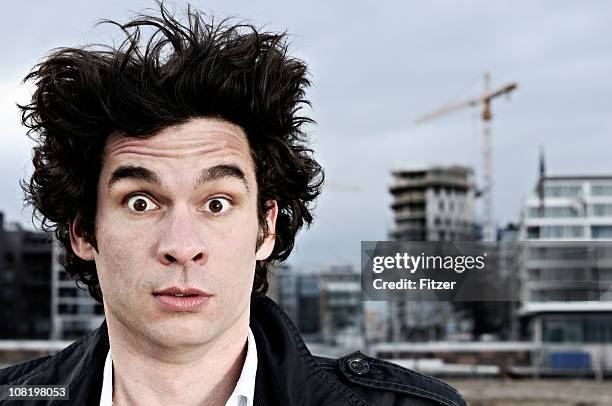 young man standing in front of construction site - hair standing on end stock pictures, royalty-free photos & images