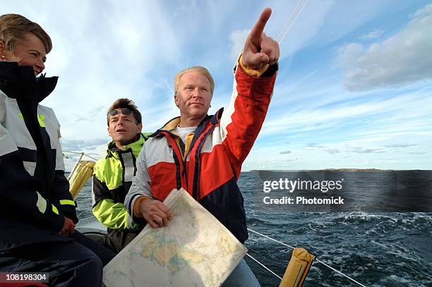 sailor with a chart in his hand pointing forward - boat captain 個照片及圖片檔