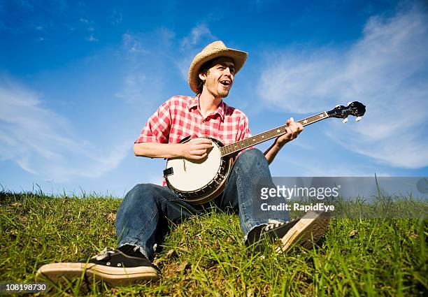 country boy plays the banjo in a rural summer meadow - hillbilly bildbanksfoton och bilder