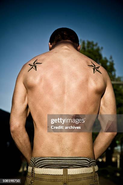 mann zeigt muskeln rücken mit tätowierungen - tattoo shoulder stock-fotos und bilder