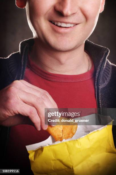 close-up of smiling man eating potato chips - chips bag stockfoto's en -beelden