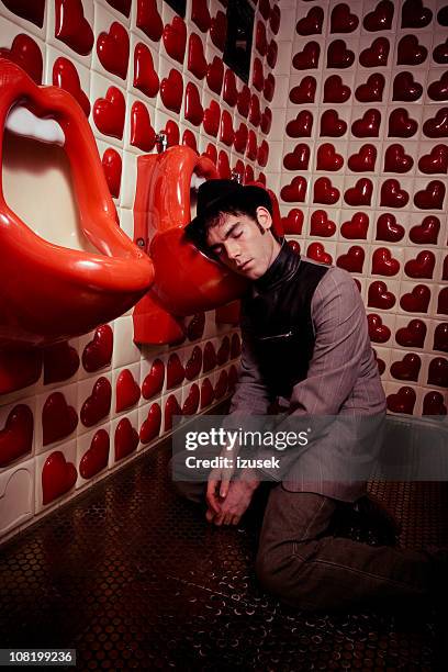 young man asleep on modern art urinals - nightclub bathroom stock pictures, royalty-free photos & images