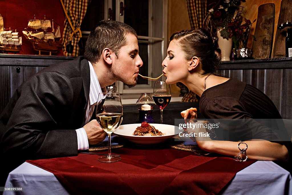 Couple Sharing Single Strand of Pasta at Dinner