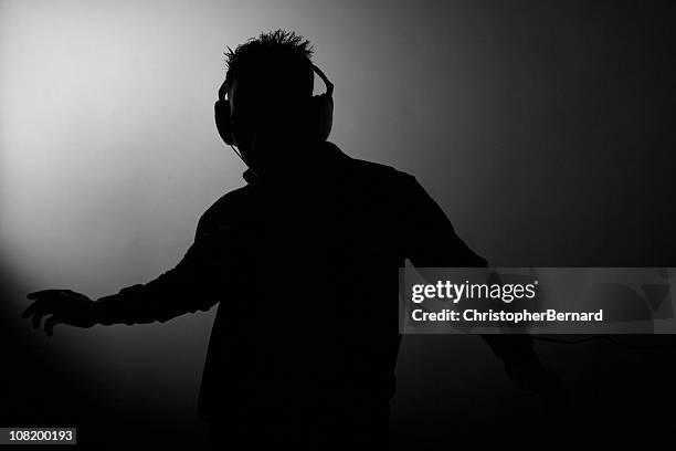 silhouette of man dancing and wearing headphones - dj stock pictures, royalty-free photos & images