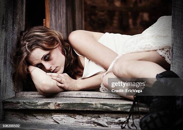 young woman with bruised black eye lying in doorway - beaten up stockfoto's en -beelden