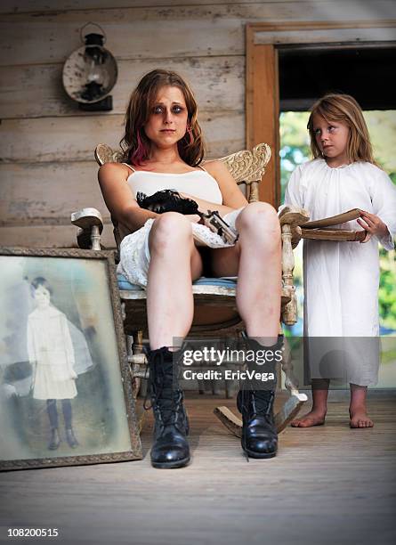 sad young woman with gun beside little angel girl - young goth girls stockfoto's en -beelden