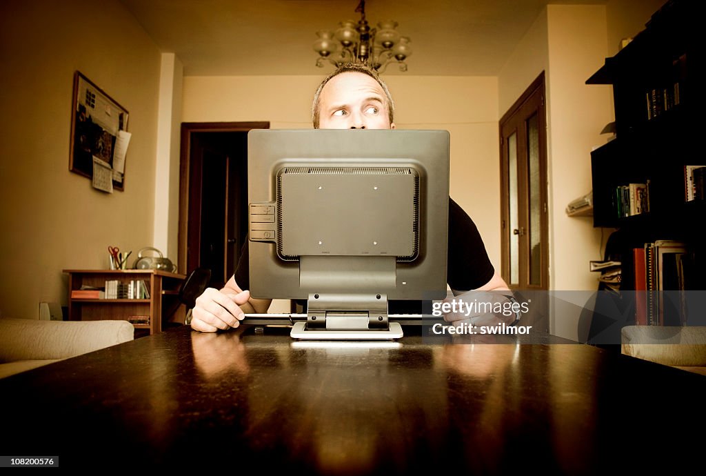 Man sitting at computer in house looking paranoid