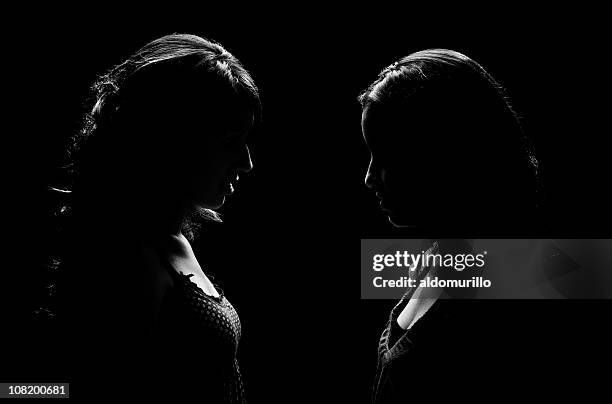 low key lit portrait of two woman facing each other - confrontation 個照片及圖片檔