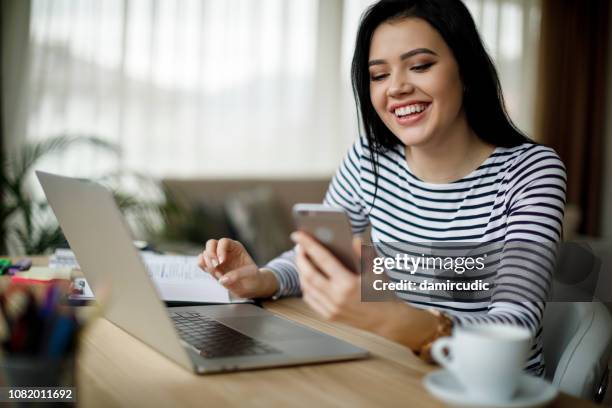 smiling young woman using mobile phone at home - girl in office stock pictures, royalty-free photos & images