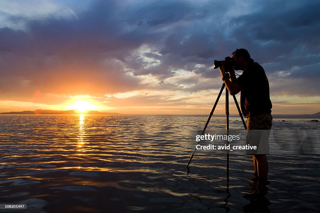 Man Photographing in Water at Sunset