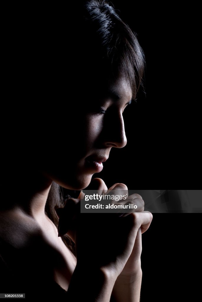 Low Key Lit Side View of Young Woman Praying