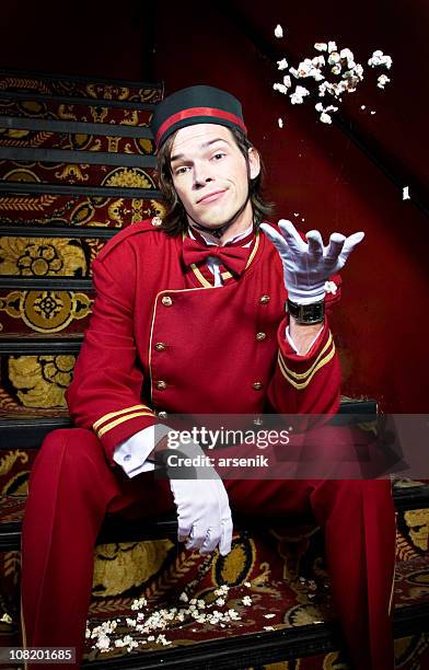 displeased movie theater usher sitting on stairs and throwing popcorn - bell boy stock pictures, royalty-free photos & images