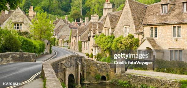 cottages lining road in green wooded valley - castle combe stock pictures, royalty-free photos & images