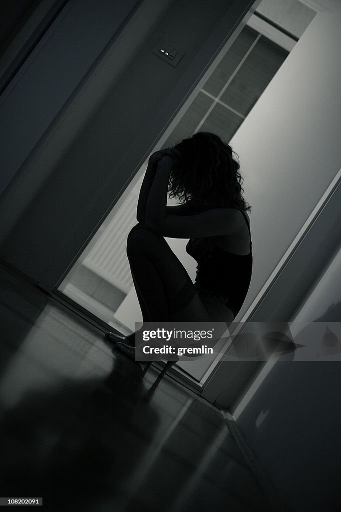 Sad Young Woman Kneeling on Floor, Low Key