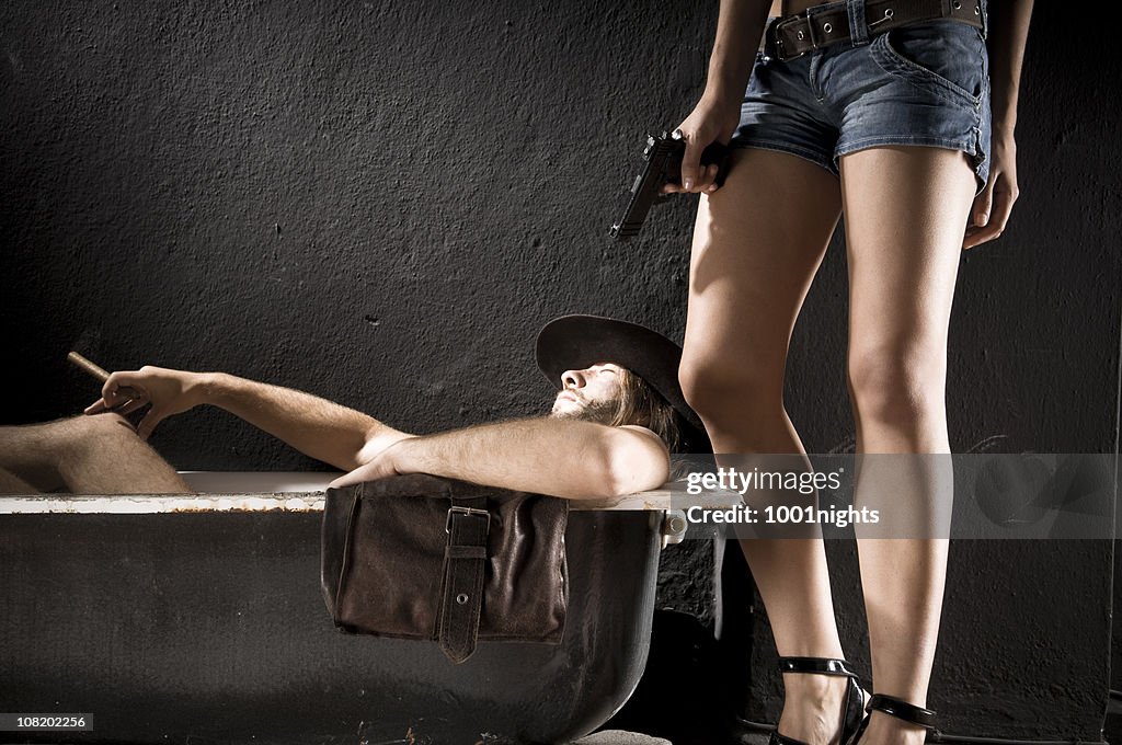 Cowboy situada na Banheira com mulher segurando a arma perto ele