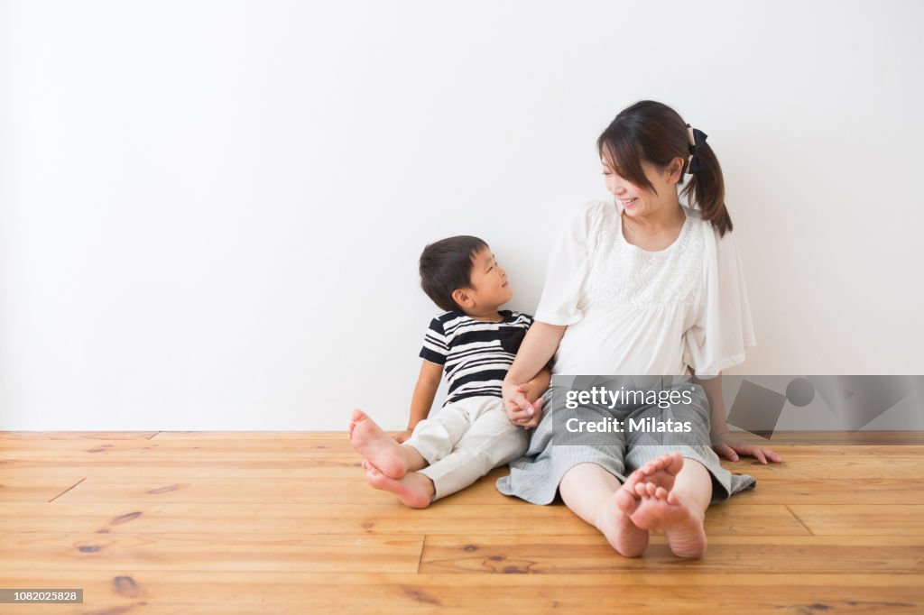 The boy and the pregnant woman who sits on the flooring