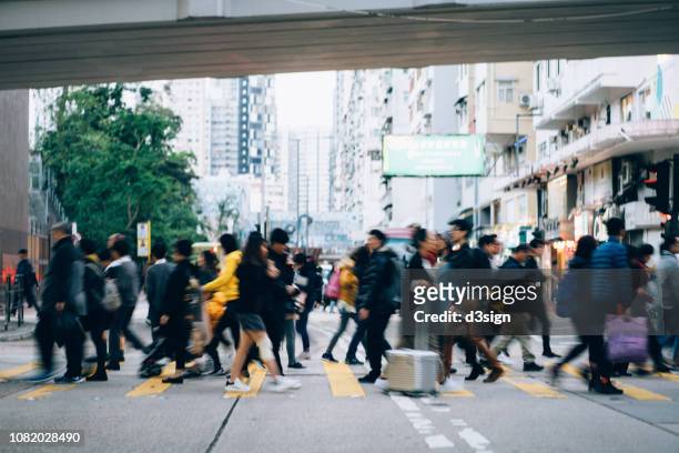 blurred motion of crowd pedestrians crossing street in pedestrian walkway against urban buildings with city scene - traffic jam china stock pictures, royalty-free photos & images
