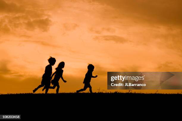 kinder at play - silhouette mädchen rennen stock-fotos und bilder