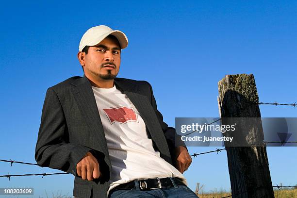 young man relaxing against fence - macho stockfoto's en -beelden