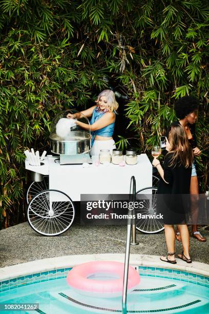 woman making cotton candy for guests during party by pool - business social gathering poolside stock pictures, royalty-free photos & images