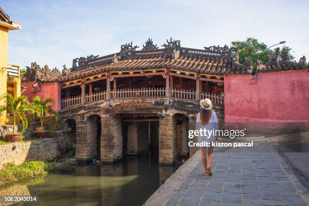 woman walking in the old town district of hoi an in vietnam during a sunny day - hoi an stockfoto's en -beelden