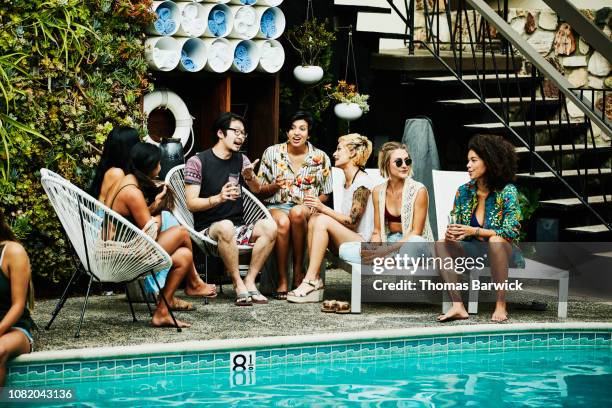 group of friends in discussion during party by pool hotel - logement social stockfoto's en -beelden