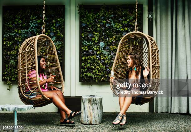 laughing friends in discussion while sitting in hanging chairs during pool party - truth be told 個照片及圖片檔