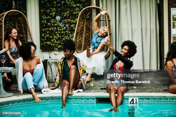 smiling woman sitting beside pool taking selfie with smart phone during party - holiday party imagens e fotografias de stock