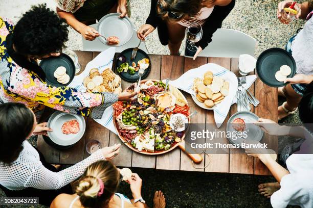 overhead view of group of friends enjoying buffet of food during party - overhead view fotografías e imágenes de stock