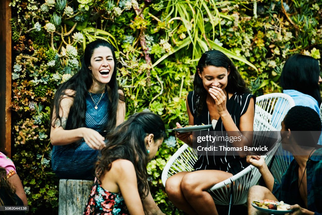 Laughing friends sharing food and drink during party