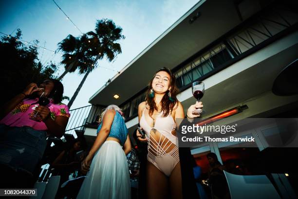 portrait of smiling woman holding glass of wine during party at hotel pool - beautiful black women in bathing suits stock pictures, royalty-free photos & images