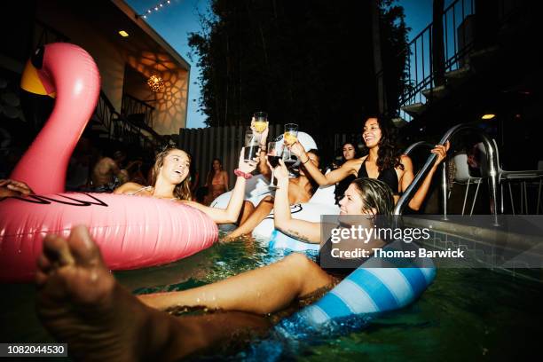 female friends toasting while floating in hotel pool during party - wine party ストックフォトと画像