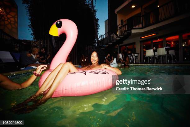 smiling woman relaxing in inflatable flamingo during party at hotel pool - man on float stock pictures, royalty-free photos & images