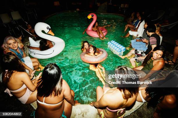 friends relaxing around hotel pool during party - pool party night stock pictures, royalty-free photos & images
