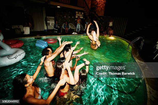 group of friends throwing woman into hotel pool during party - pool party night stock pictures, royalty-free photos & images