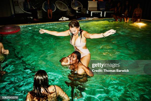 woman riding on friends shoulders during party in hotel pool - the beauty of power event stock-fotos und bilder