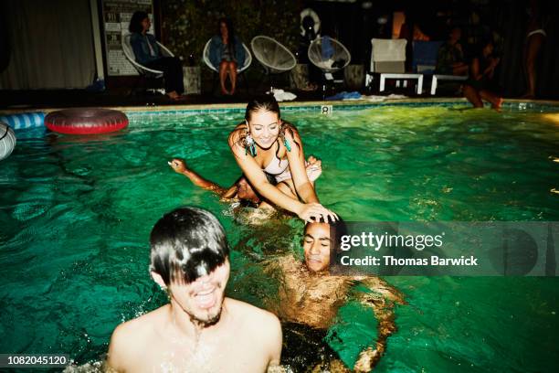 smiling woman sinking friend in hotel pool during party - older woman wet hair stock pictures, royalty-free photos & images