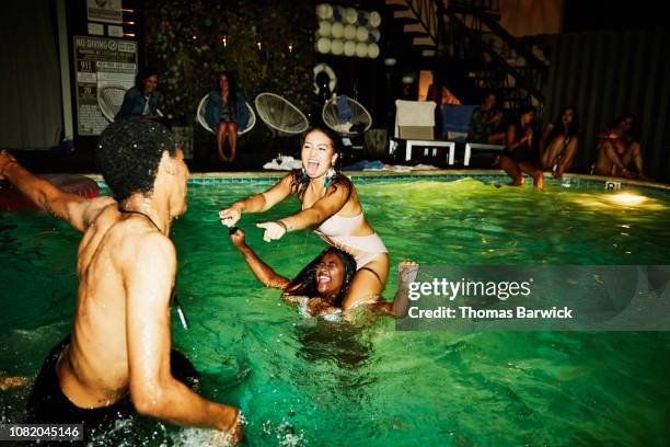 woman taunting friends after winning chicken fight in hotel pool during party - swimming pool night stock pictures, royalty-free photos & images