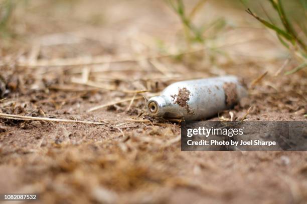 discarded nitrous oxide canister in the dirt - festival rubbish stock pictures, royalty-free photos & images