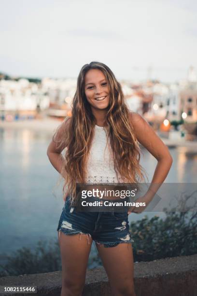 portrait of teenage girl standing against sea in city during sunset - crop top stock pictures, royalty-free photos & images