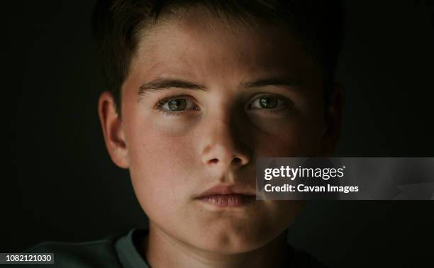 close-up portrait of serious boy standing in darkroom at home - staring stock pictures, royalty-free photos & images
