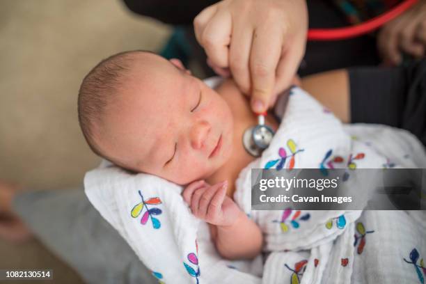 cropped hand of midwife examining newborn baby girl carried by mother at home - home birth stock-fotos und bilder