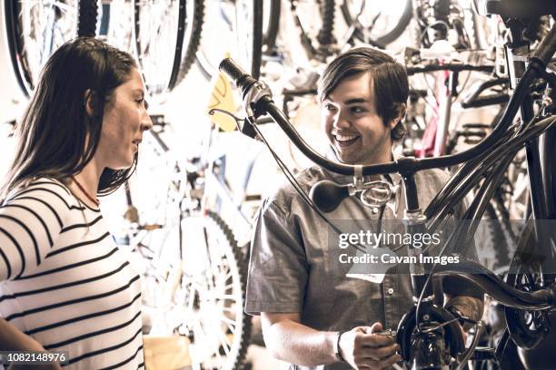 male owner showing bicycle to female customer in store - buying a bike stock-fotos und bilder