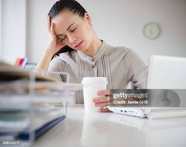 woman exhausted at desk with coffee - stanchezza foto e immagini stock